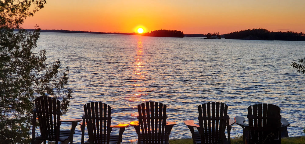 Gorgeous sunset over a Wisconsin lake with a row of Adirondack chairs facing the lake