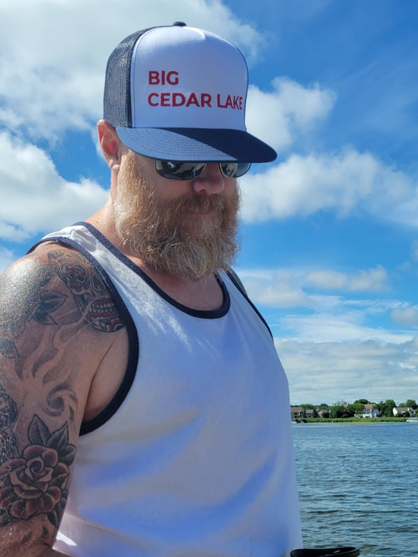 Man looking down showing his trucker hat which has a white front and "BIG CEDAR LAKE" written in red caps